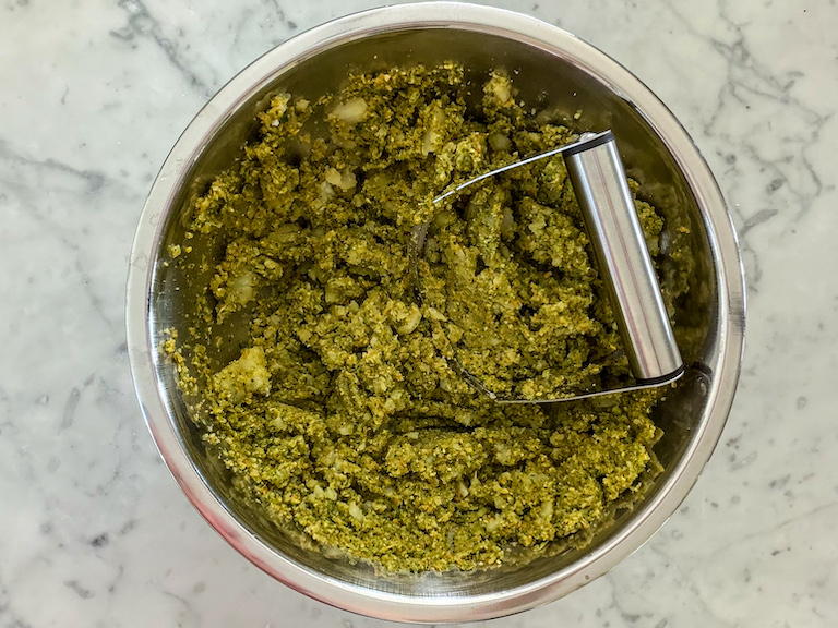 veggie mash in a bowl with a pastry blender