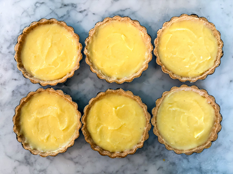 six miniature tart shells filled with bright yellow lemon curd