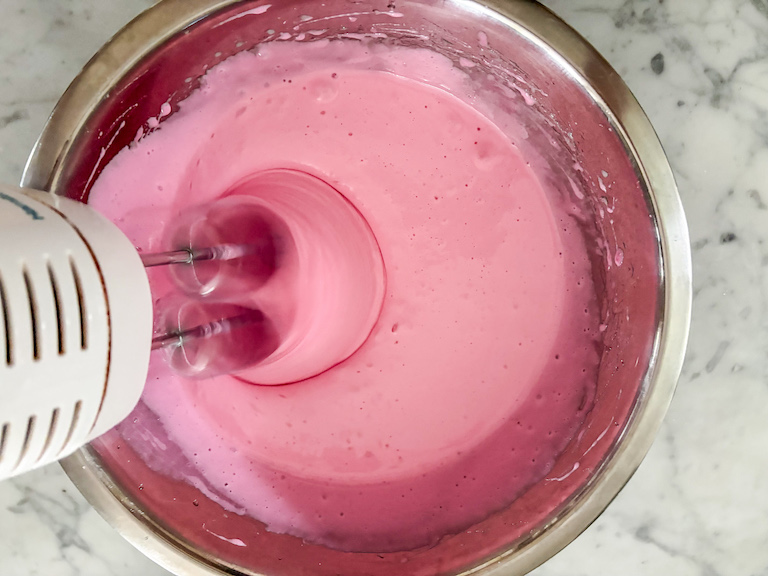 Mixing strawberry marshmallow fluff with a hand mixer