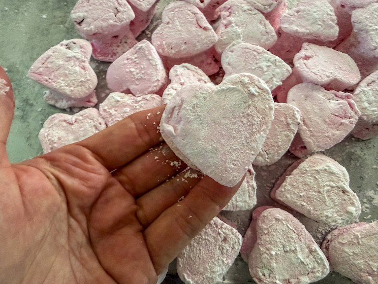 hand holding a pink heart shaped marshmallow