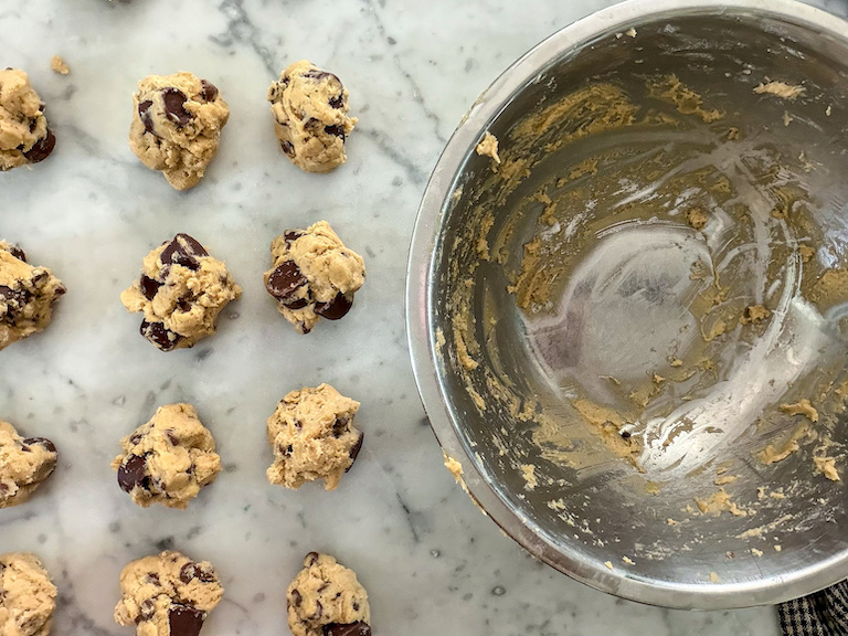 Balls of dough next to an empty metal bowl