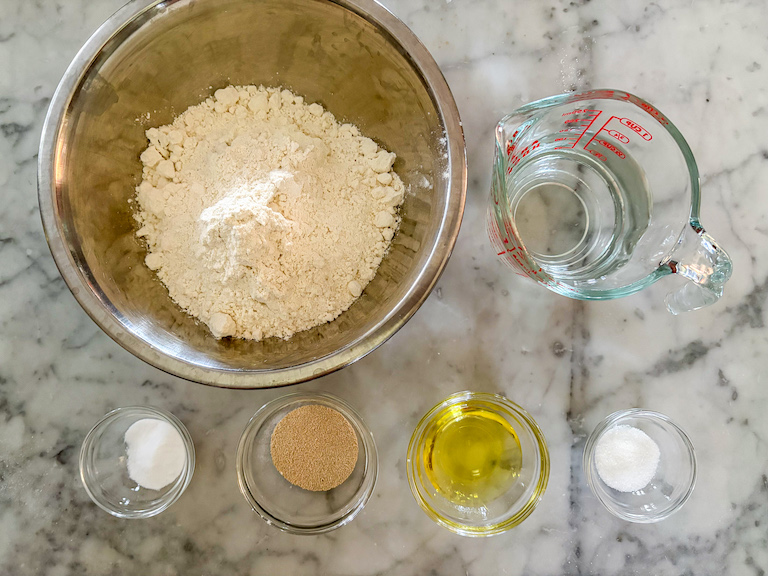 Pizza dough ingredients arranged on a marble surface