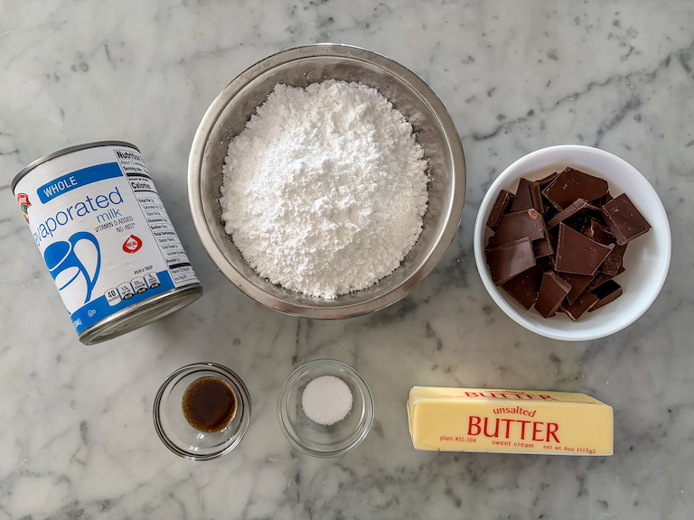 Ingredients for homemade hot fudge sauce arranged on a marble surface
