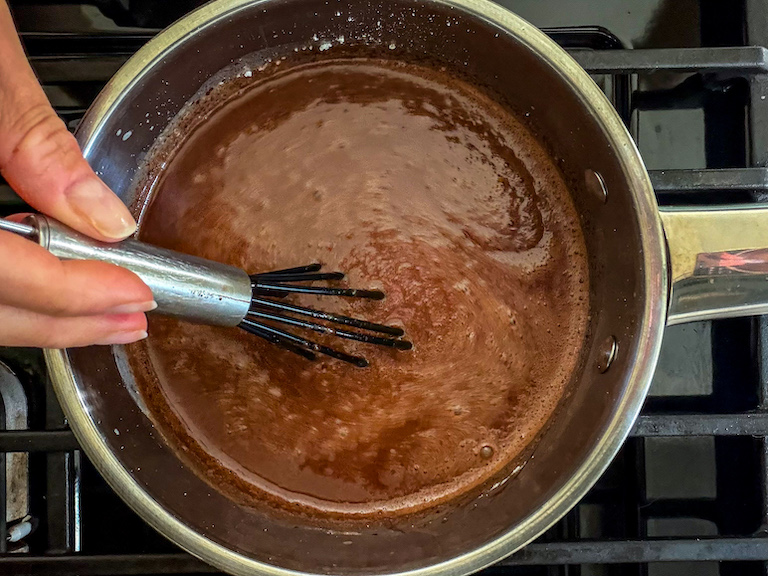 Hand whisking hot fudge sauce on the stovetop