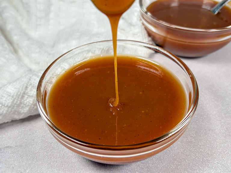 Drizzling homemade caramel sauce into a bowl