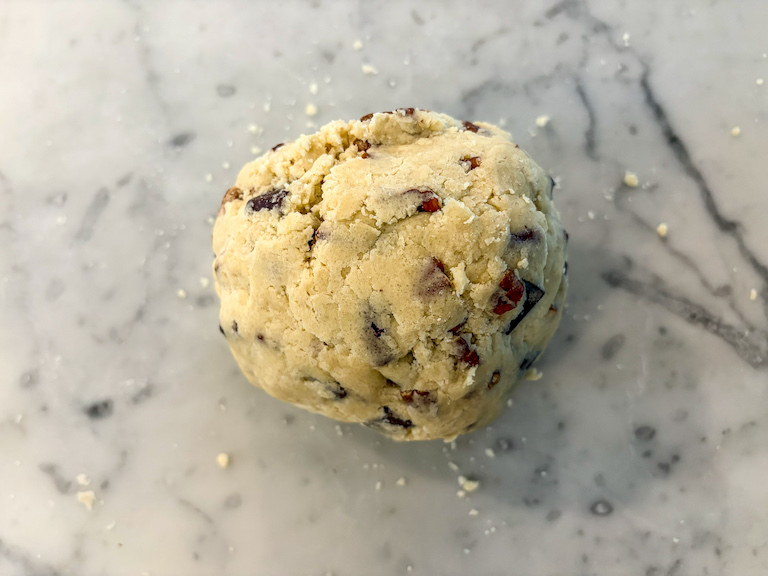 A ball of shortbread dough on a marble countertop