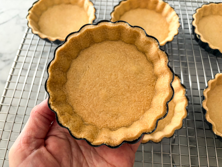 hand holding a mini fluted tart shell in a pan