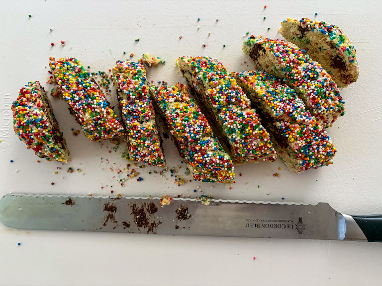 Slicing rainbow biscotti with a serrated knife