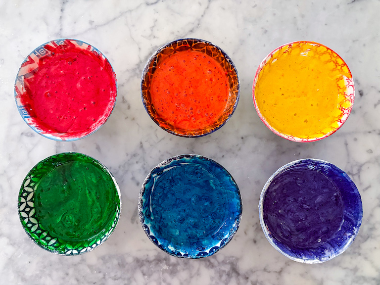 Six bowls of cake batter in rainbow colors
