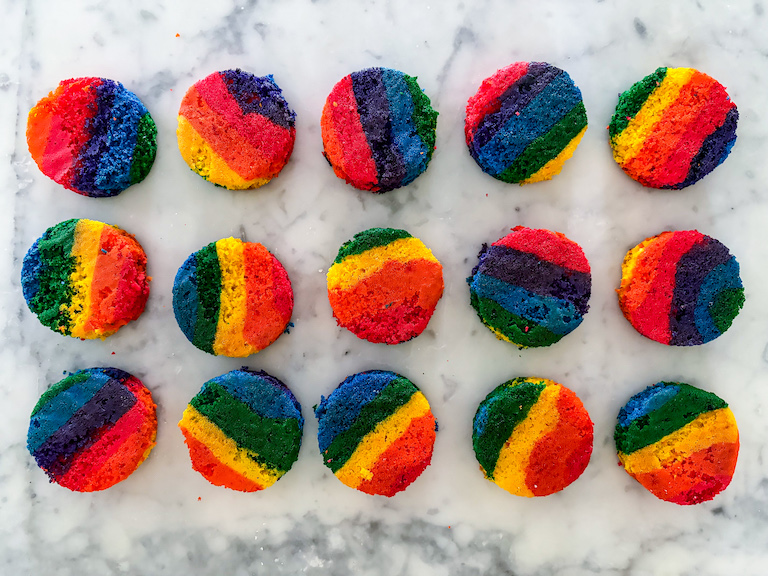 Discs of rainbow cake arranged on a marble surface