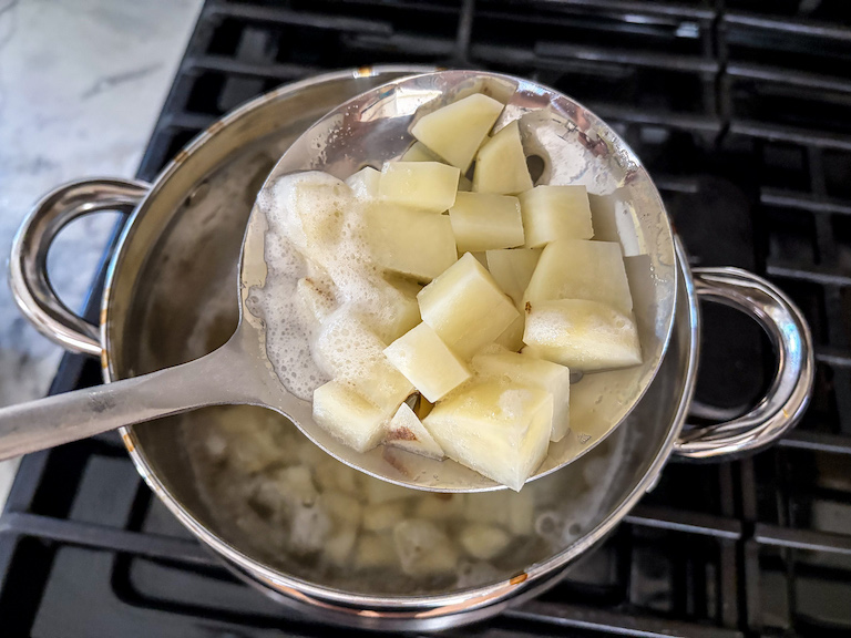 Spooning boiled potatoes with a slotted spoon