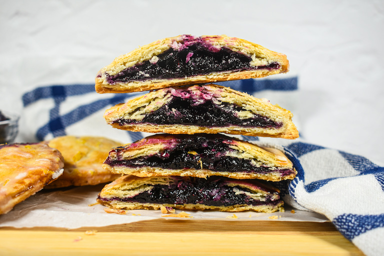a stack of blueberry hand pies on a cutting board