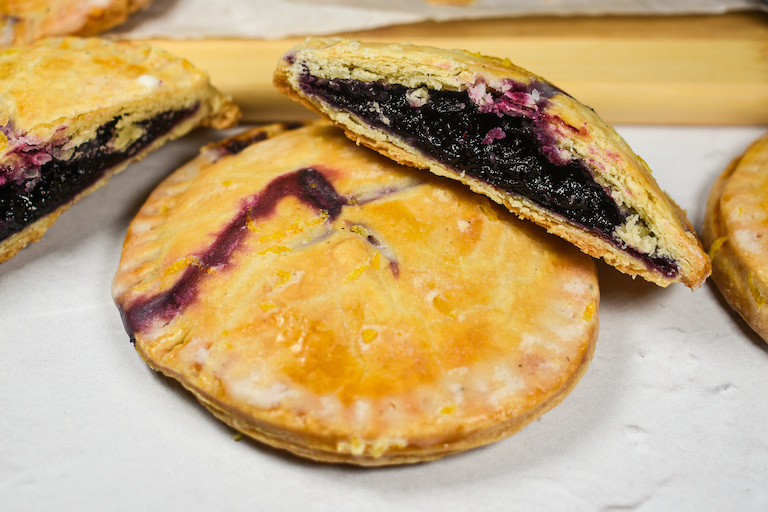 sliced blueberry hand pies on a white surface