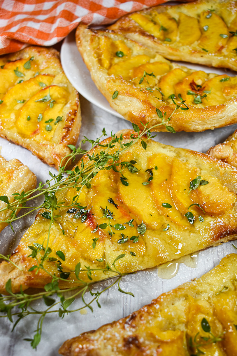 Peach mascarpone puff pastry triangles garnished with sprigs of thyme