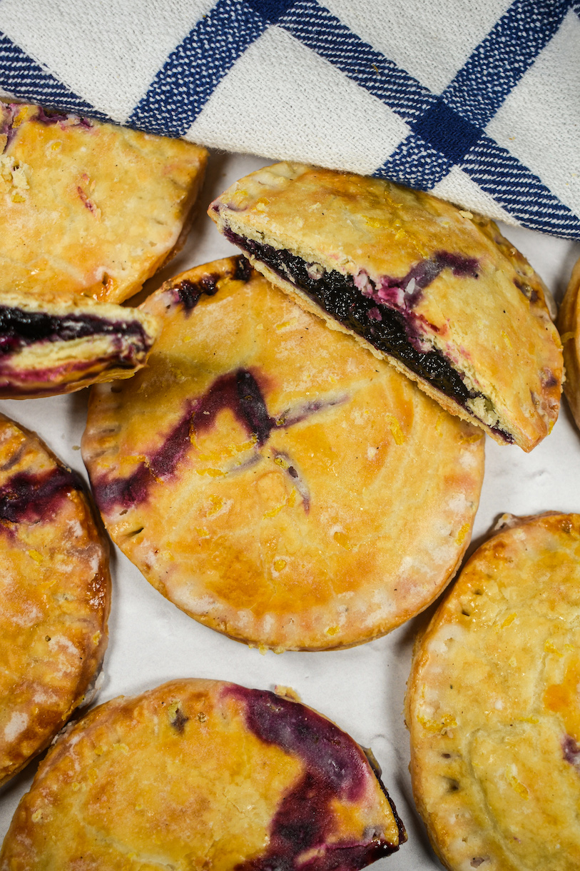blueberry hand pies on a white surface with a plaid towel