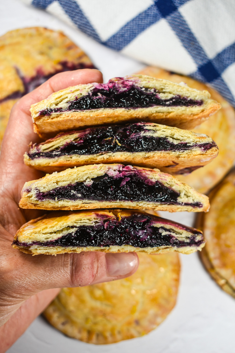 hand holding a stack of blueberry hand pies