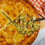 scooping a meatless lentil pot pie with a metal spoon