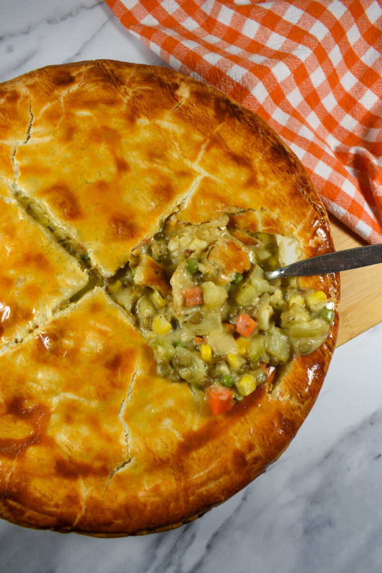 scooping a meatless lentil pot pie with a metal spoon