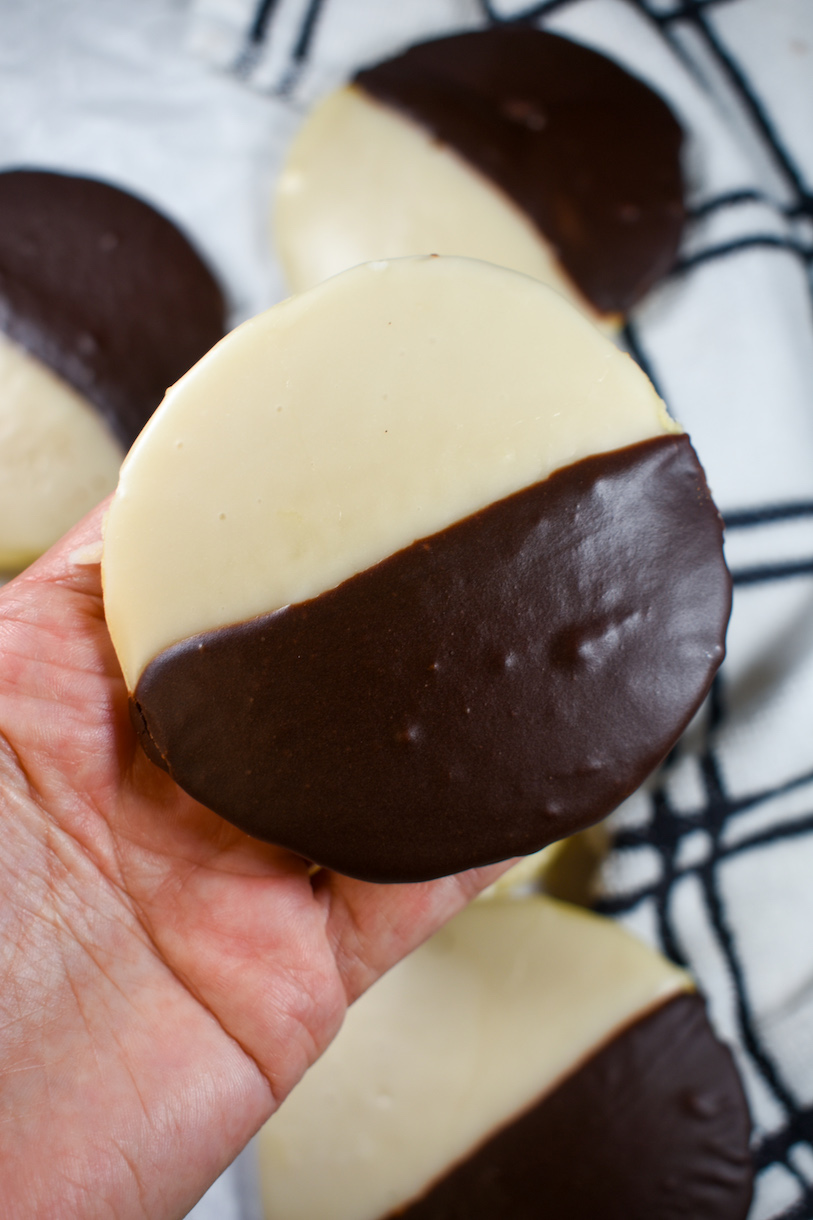 hand holding a new york black and white cookie with chocolate and vanilla frosting