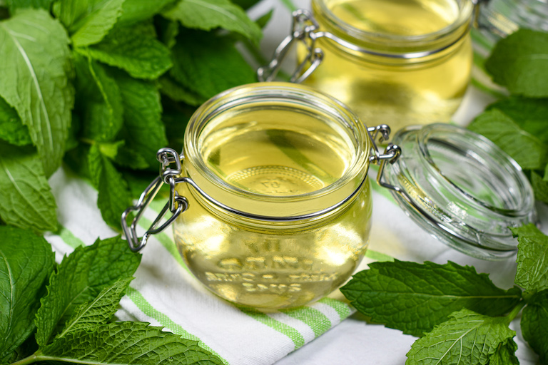 Jars of mint syrup surrounded by fresh mint leaves
