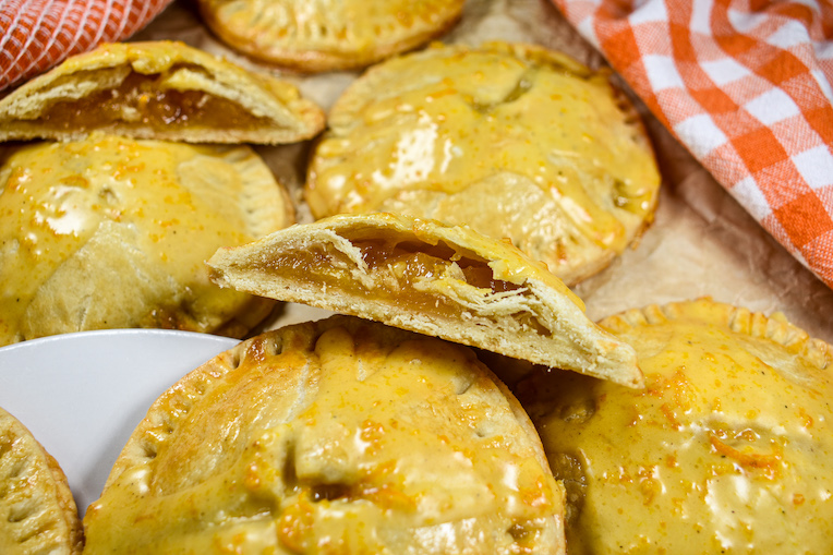Sliced and whole peach hand pies on a sheet of brown parchment