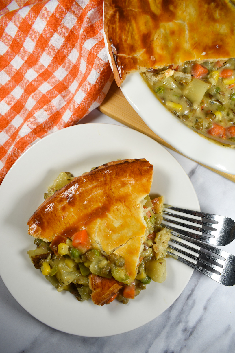 a slice of vegetarian pot pie on a white plate with two metal forks