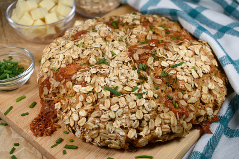a loaf of soda bread with cheddar and herbs, arranged on a wooden cutting board