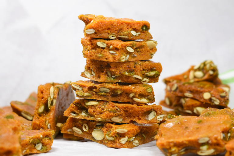 a stack of homemade pumpkin seed brittle against a white backdrop