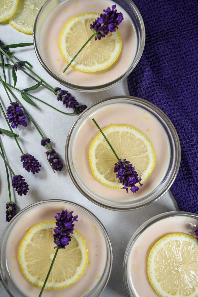 Lavender lemon possets on a white surface with lavender flowers and a purple towel