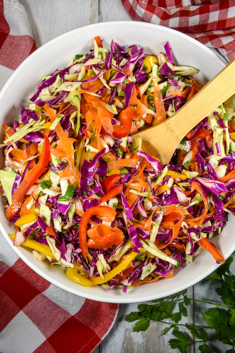 a bowl of rainbow coleslaw with a sopoon