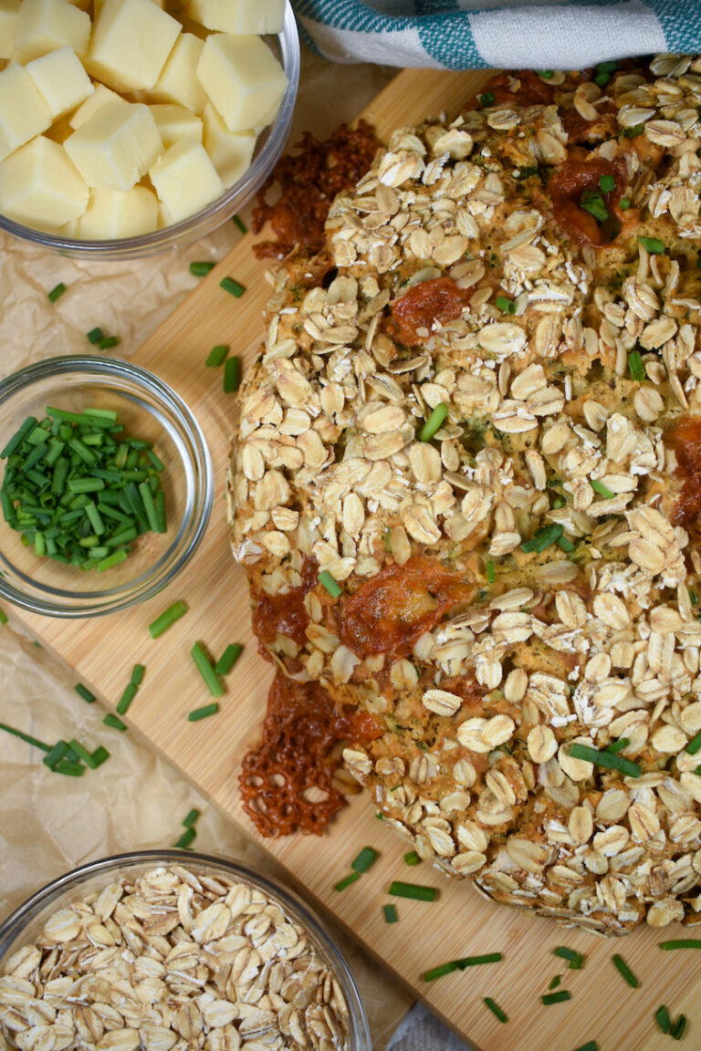a loaf of cheddar and herb soda bread on a wooden cutting board