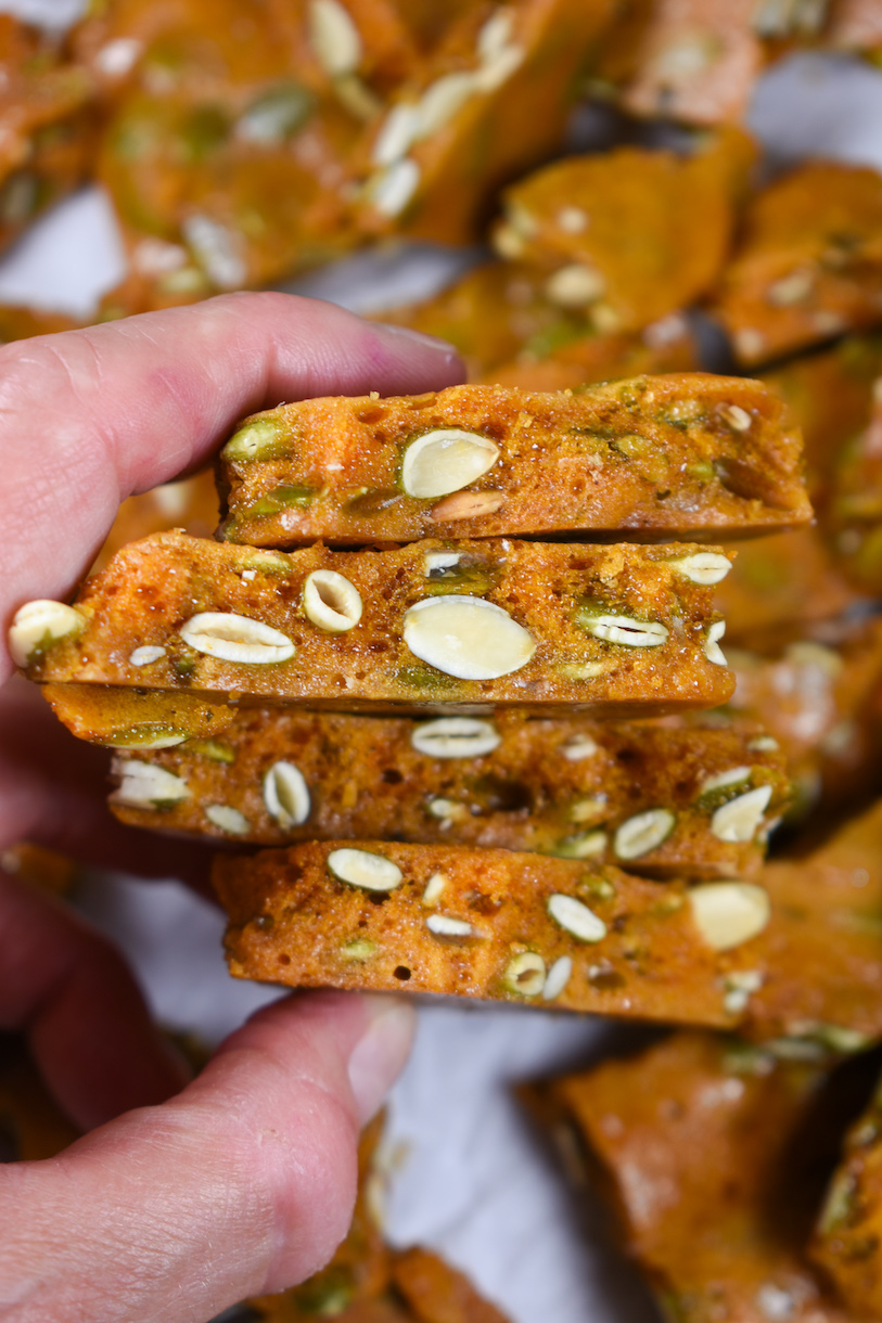 hand holding a stack of pieces of pumpkin seed brittle
