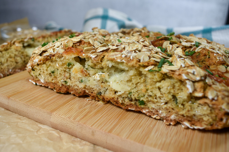 a sliced loaf of cheddar and herb soda bread with cheese oozing from the middle