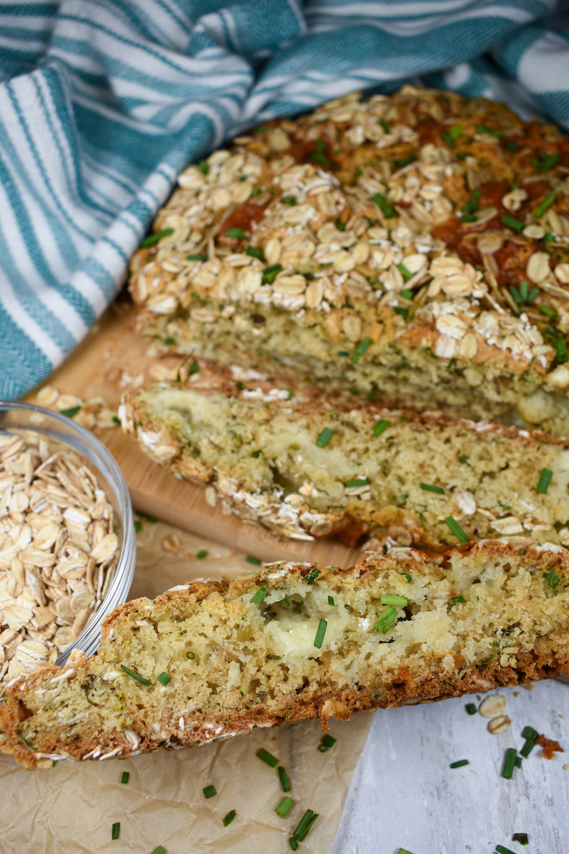 sliced loaf of cheddar herb soda bread with a green striped towel