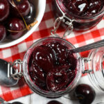 looking down at jars of cherry compote surrounded by fresh cherries