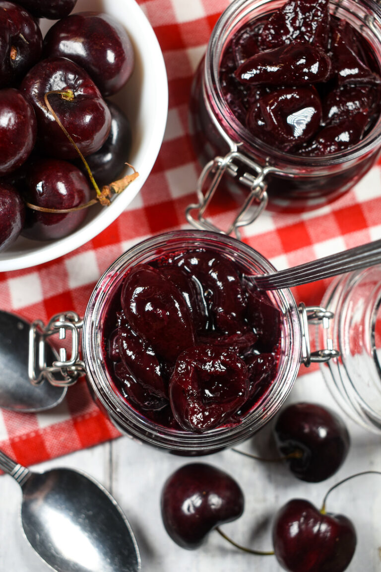 looking down at jars of cherry compote surrounded by fresh cherries