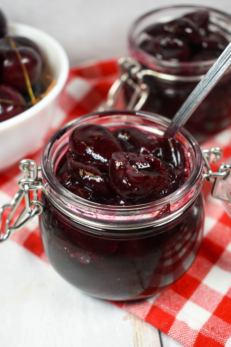 a jar of cherry compote with a spoon
