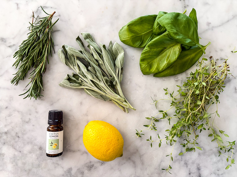 herbs, lemon oil, and a lemon on a marble surface