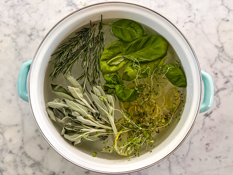 herbs in a pot of water on a marble surface