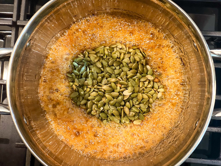 stirring pumpkin seeds into sugar syrup