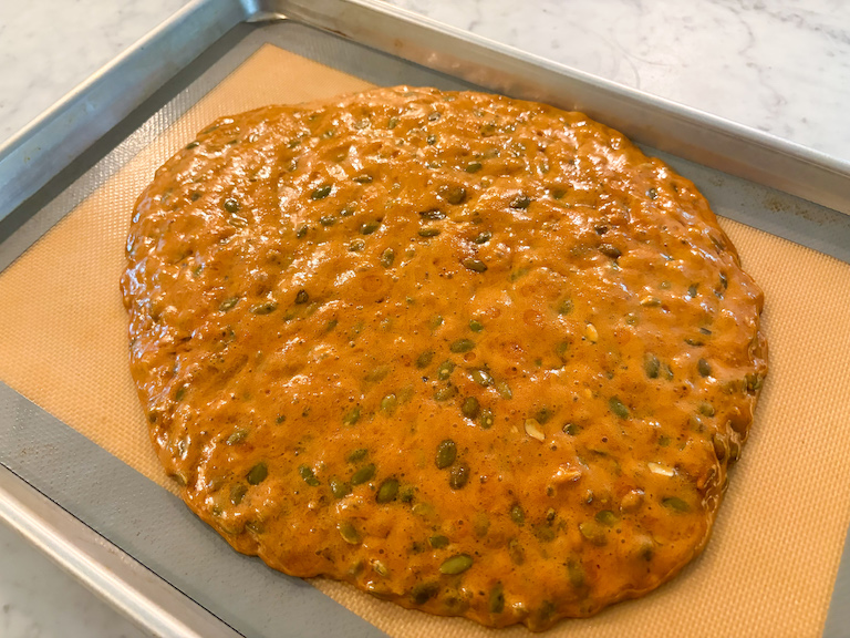 a slab of hot pepita brittle cooling on a silicone mat