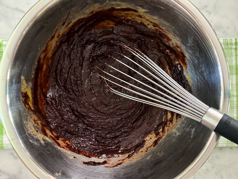 brownie batter in a metal bowl with a whisk