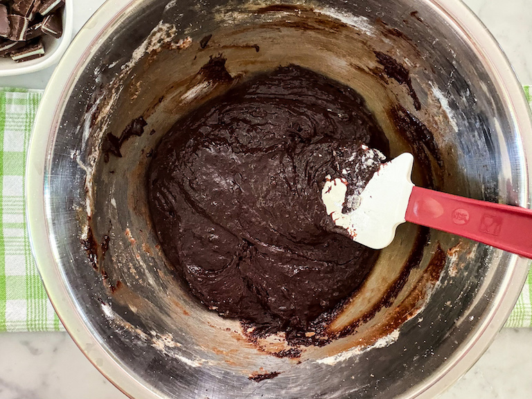 rubber spatula folding brownie batter in a bowl