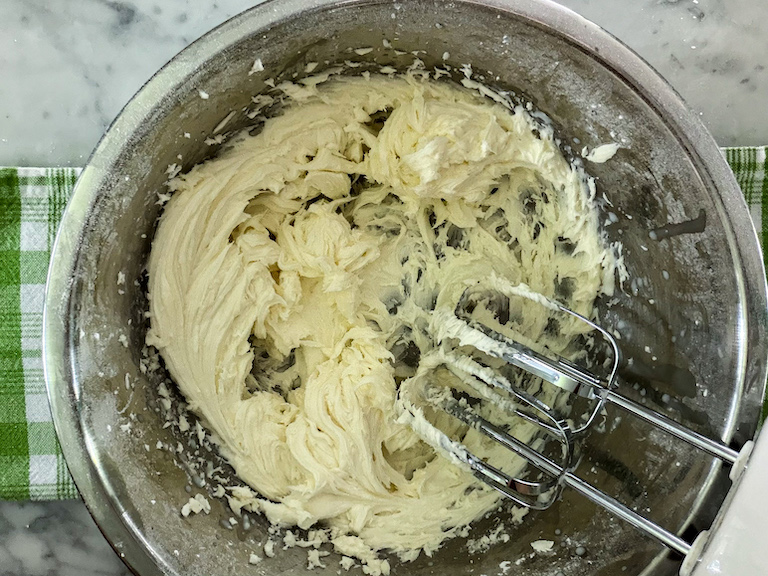 mixing bowl of buttercream with beaters