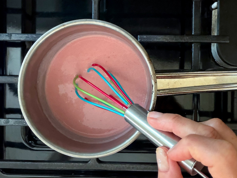 whisking cream and raspberries in a small pan