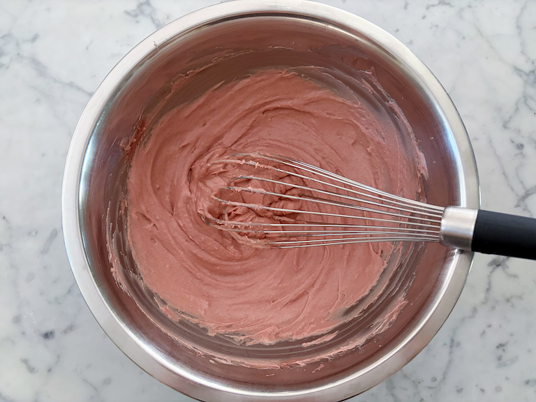 a bowl of ruby raspberry ganache with a whisk