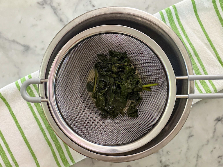 straining mint leaves through a mesh strainer