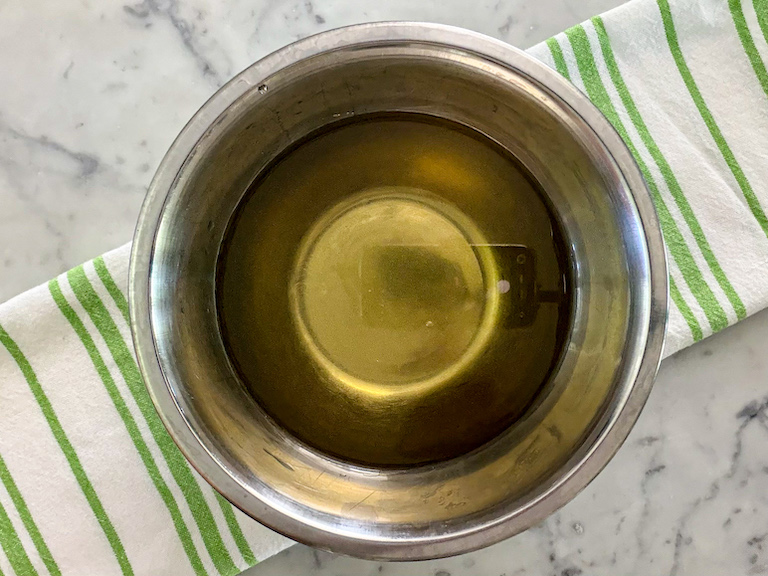 A metal bowl of homemade mint simple syrup from real mint leaves