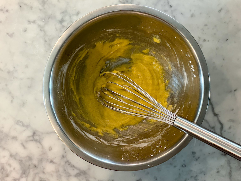 whisking pastry cream ingredients in a metal bowl