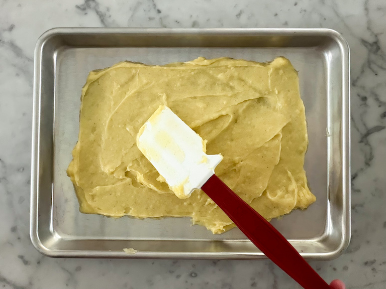 spreading pastry cream on a tray with a spatula
